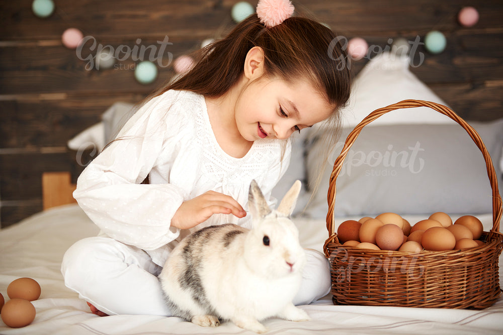 Affectionate girl stroking her rabbit in bed