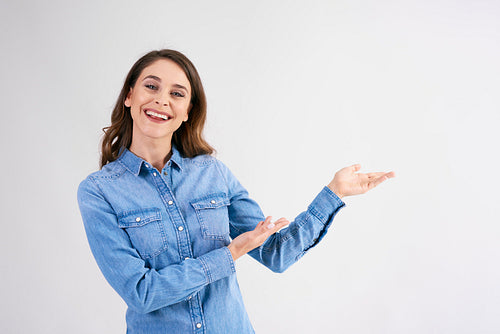 Smiling, young woman pointing at copy space at studio shot