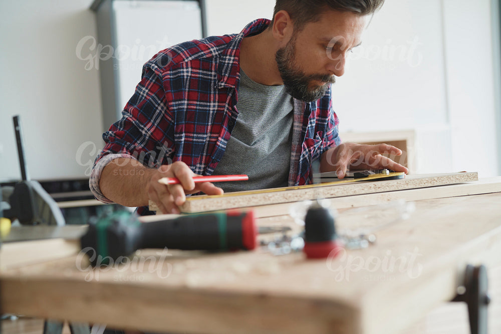 Carpenter measuring and cordless drill lying on the table