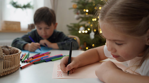 Writing letter to Santa Claus by cute little girl with her brother