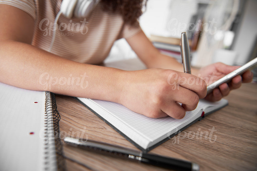 Close up of girl’s hand writing on notebook
