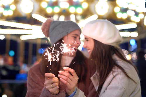 Female friends with sparklers on Christmas market