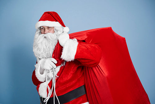 Tired santa claus carrying heavy sack