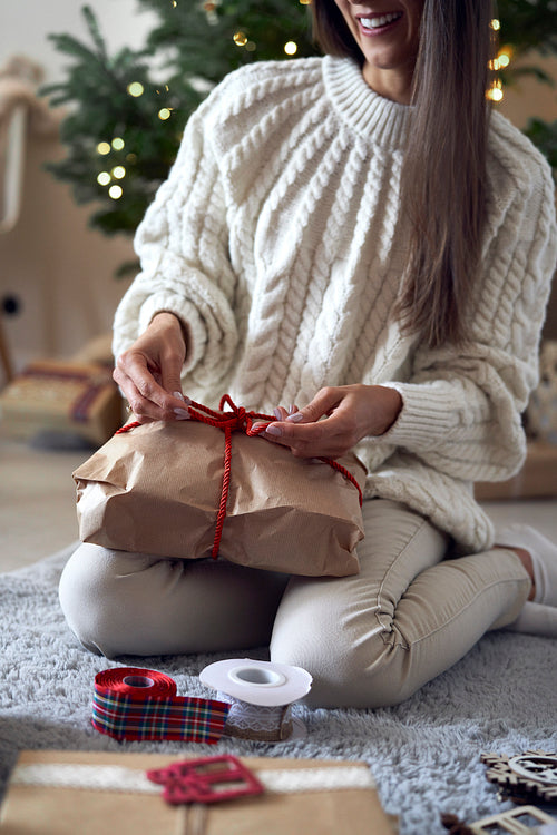 Low section of caucasian woman packing Christmas gift at home