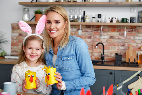 Portrait of smiling mother and daughter with handmade Easter chickens