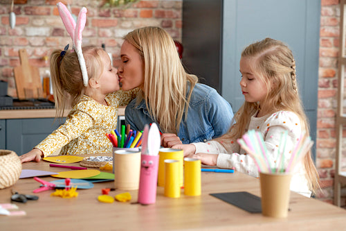 Cute kissing mom with daughters during preparing Easter decorations