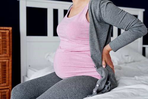 Unrecognizable pregnant woman feeling pain in the back