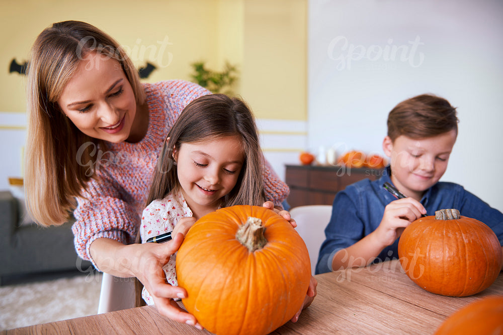 Mother and children drawing on pumpkin