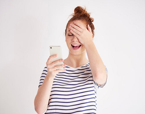 Girl using mobile phone and laughing at studio shot
