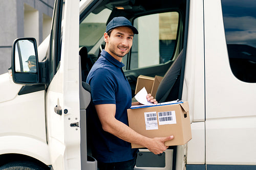 Portrait of smiling courier with packages and documents