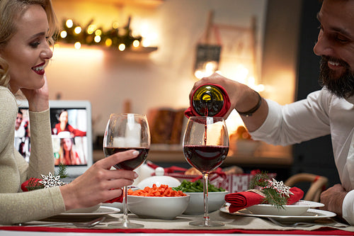 Happy couple pouring wine during Christmas dinner