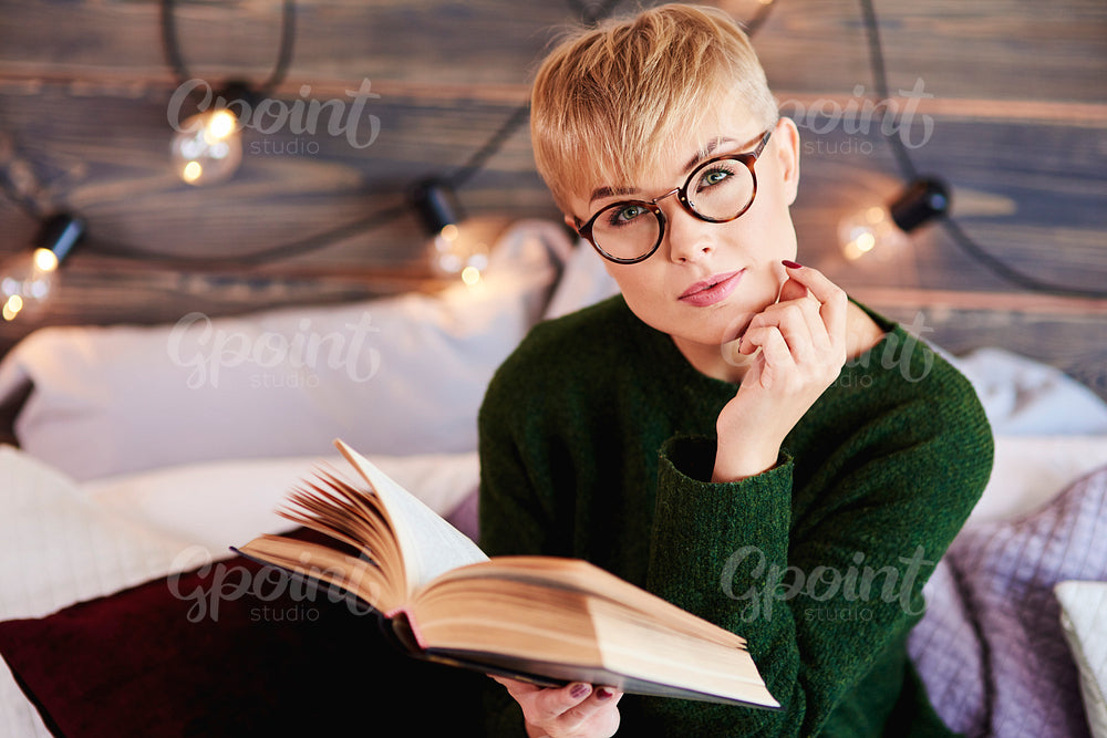 Portrait of beautiful girl reading a book in bed