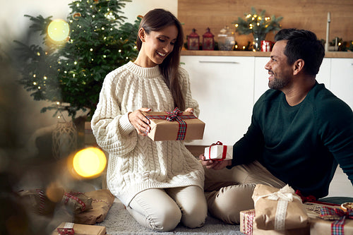 Multi ethnicity couple sharing Christmas present together at home