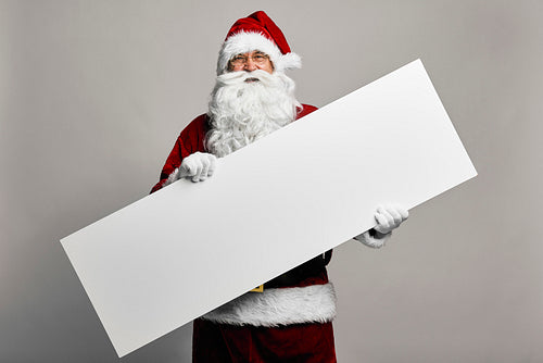 Caucasian Santa Claus on grey background holding a long copy space sign