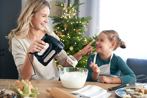 Caucasian mother and daughter preparing sweet food in the kitchen before Christmas
