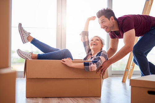 Happy couple having fun with boxes during move house
