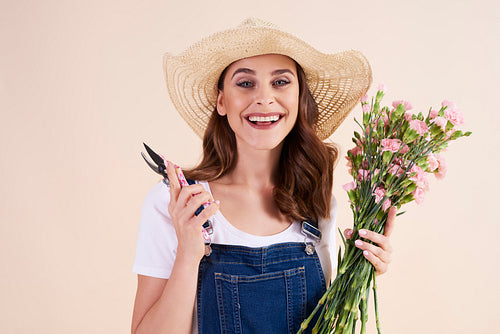 Portrait of smiling woman holding pruning shears and flowers