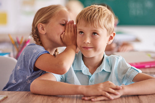 Boy and girl whispering in classroom