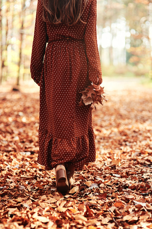 Woman walking away with an autumnal leaf
