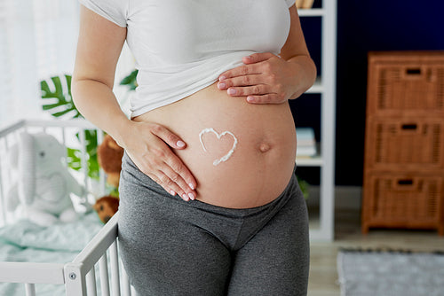 Pregnant woman and heart shape made of body lotion
