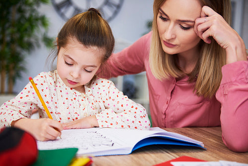 Focused mother helping child with homework
