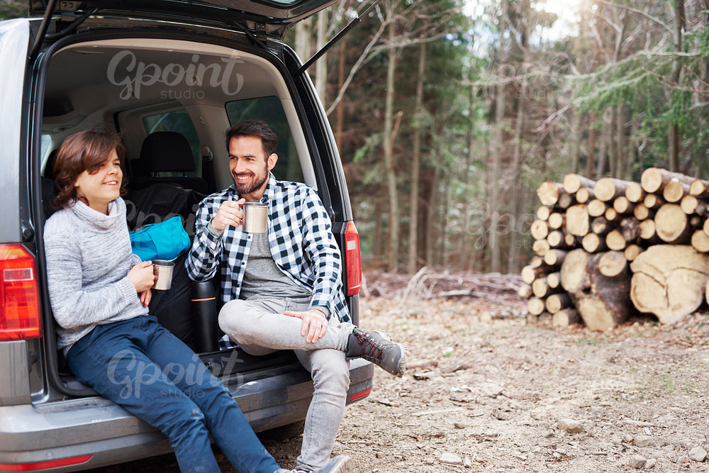 Cheerful boy and his dad drinking tea during spring hiking trip