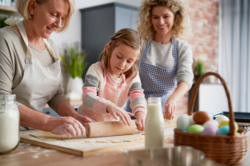 Three generations of women rolling dough