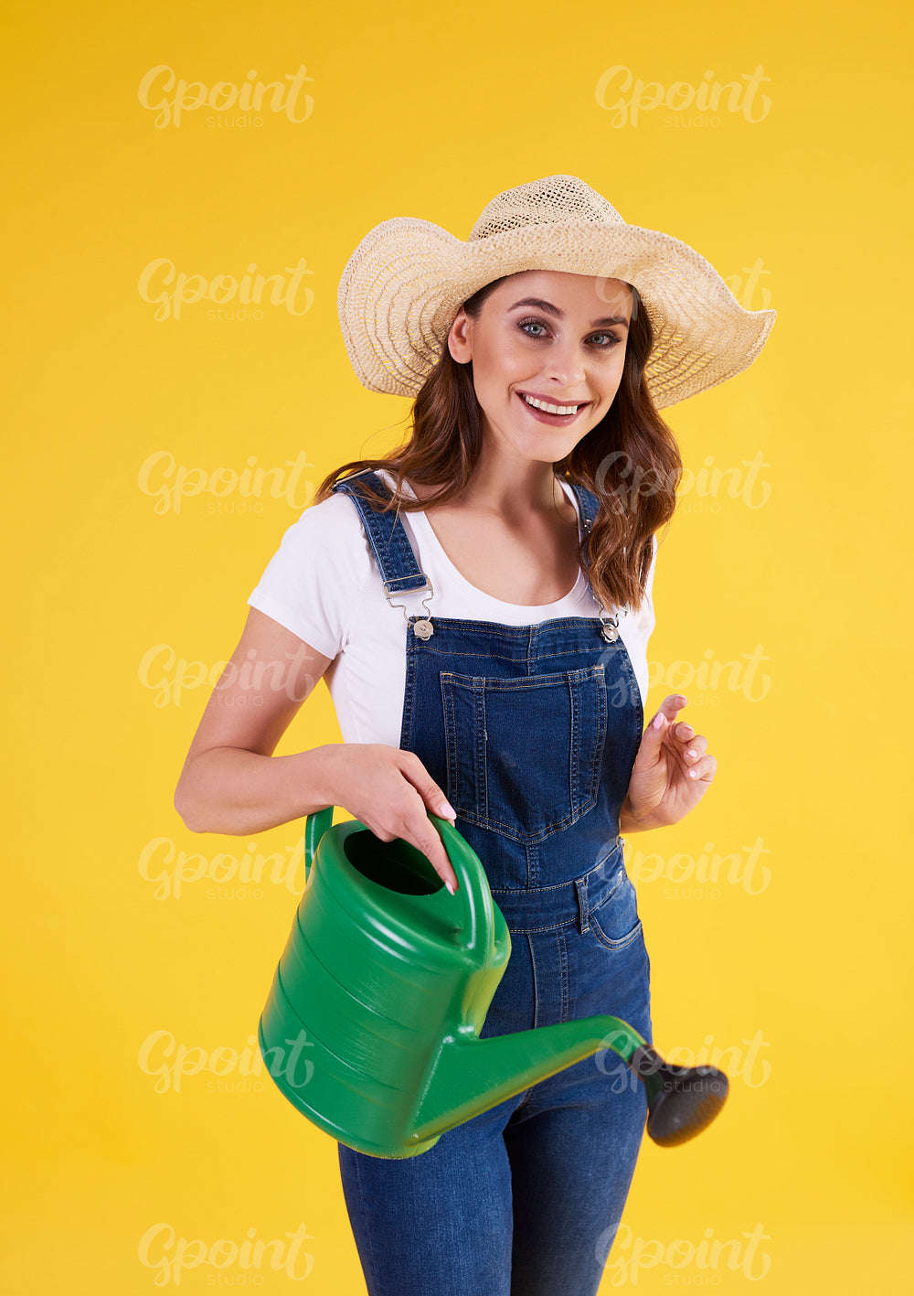 Smiling woman holding watering can in studio shot