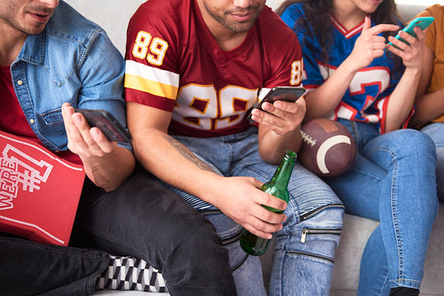 American football fans siting and scrolling the phones