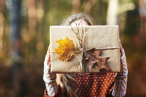 Close up of woman’s hands holding gift in autumn forest