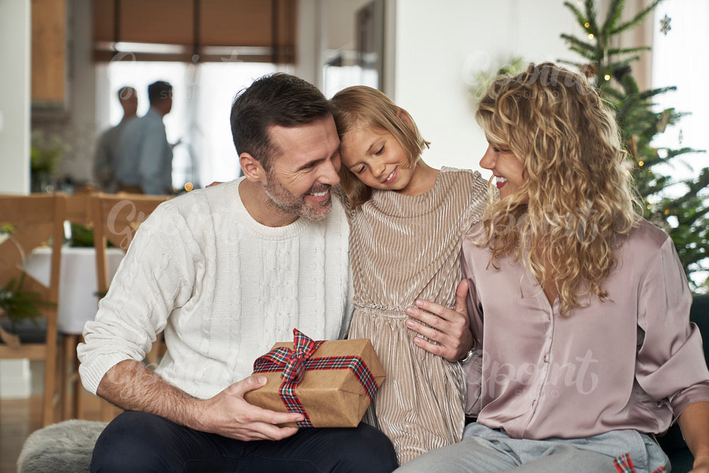 Elegant caucasian family of parents and girl sitting and holding Christmas presents