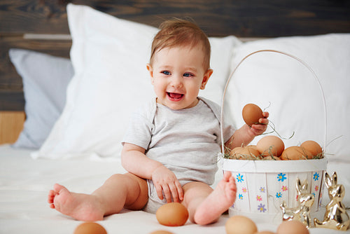 Charming baby girl with easter basket of eggs