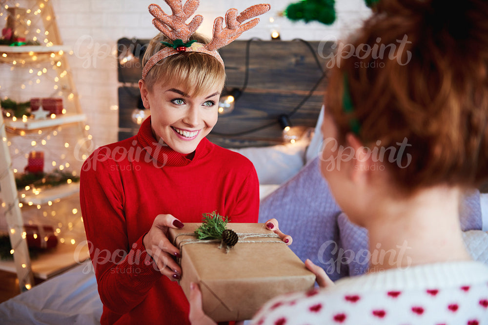 Girl giving Christmas present to her friend