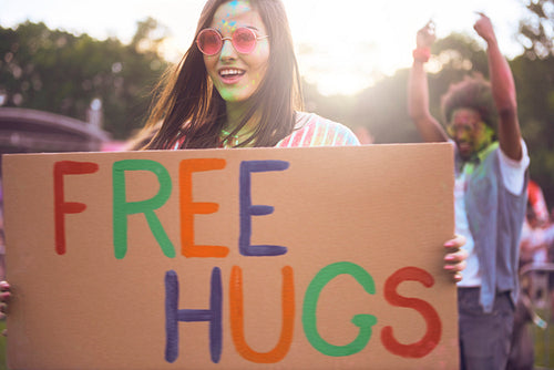 Happy woman holding banner "free hugs" during summer music festival