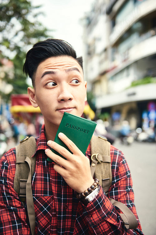 Young Asian man holding a passport case