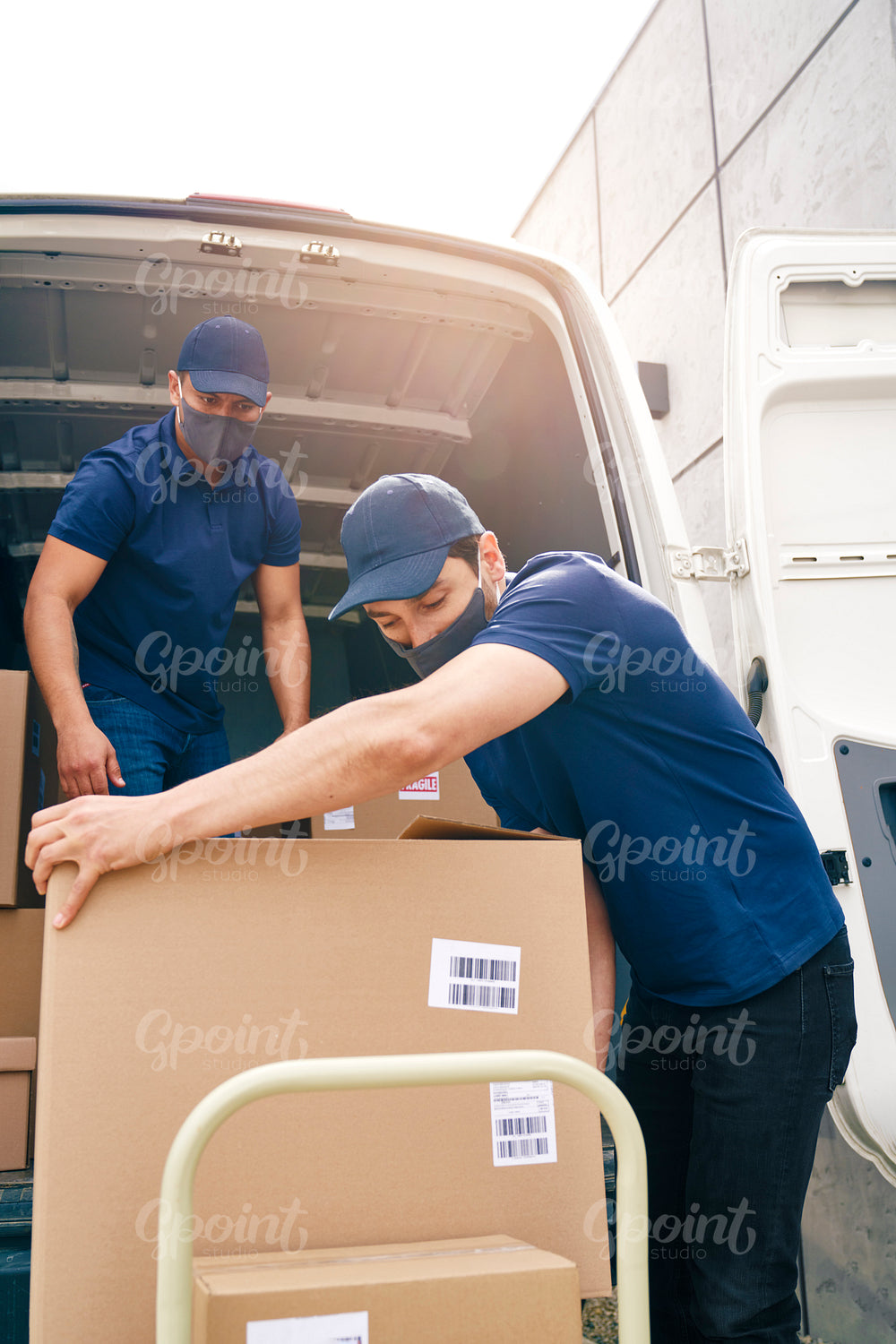 Two couriers in protective masks unloading packages