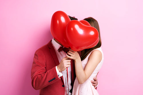 Couple kissing behind balloons