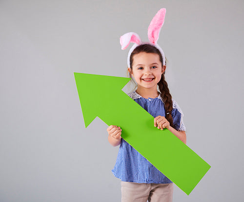 Smiling girl with green arrow pointing at copy space