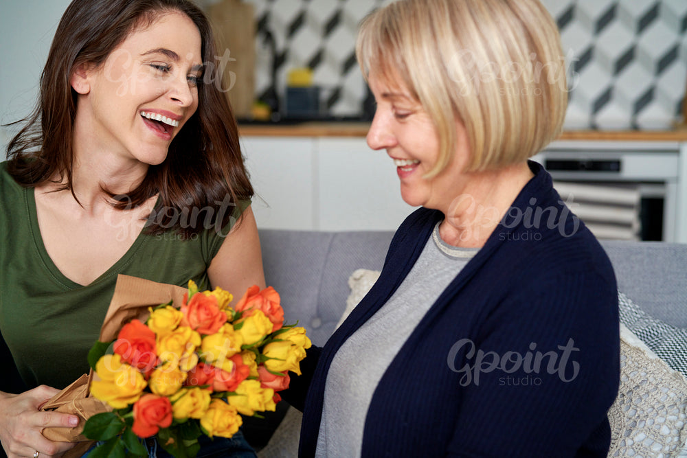 Happy woman giving mom bouquet of flowers