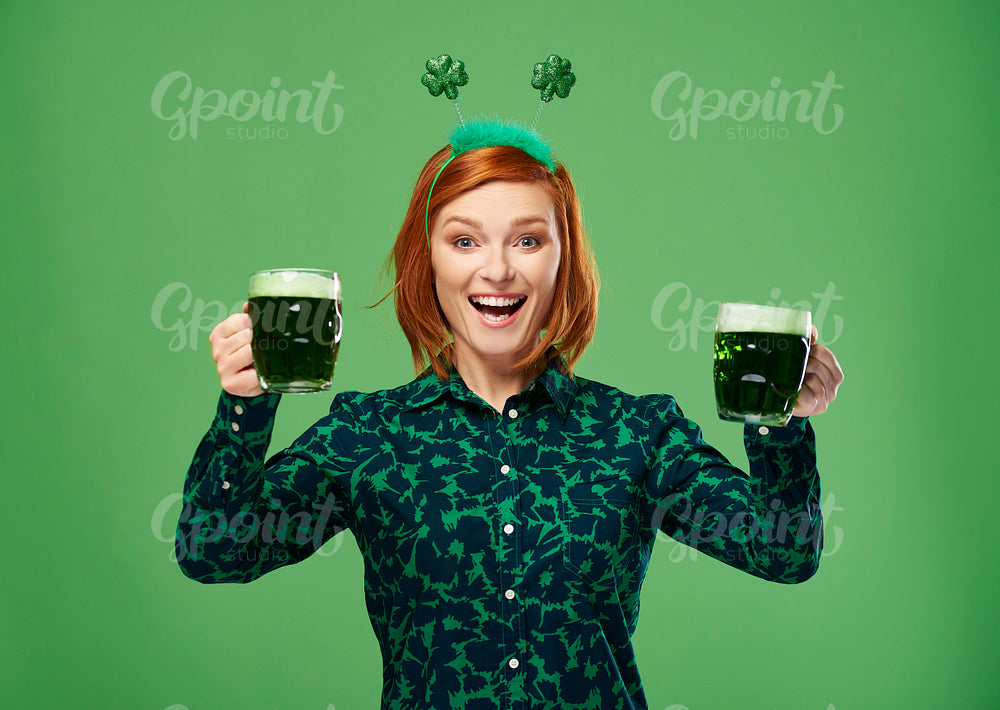 Excited woman with beer making a toast in studio shot