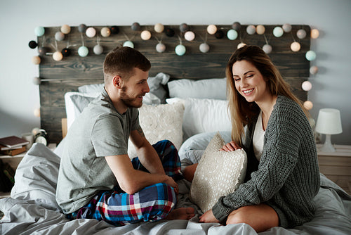 Cheerful couple talking in bed