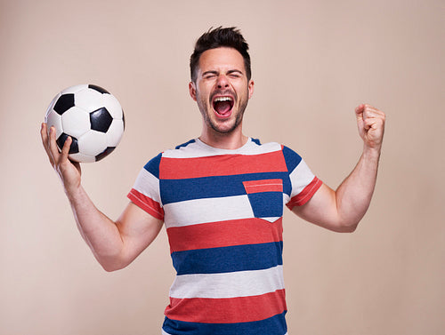 Ecstatic male fan with soccer ball cheering