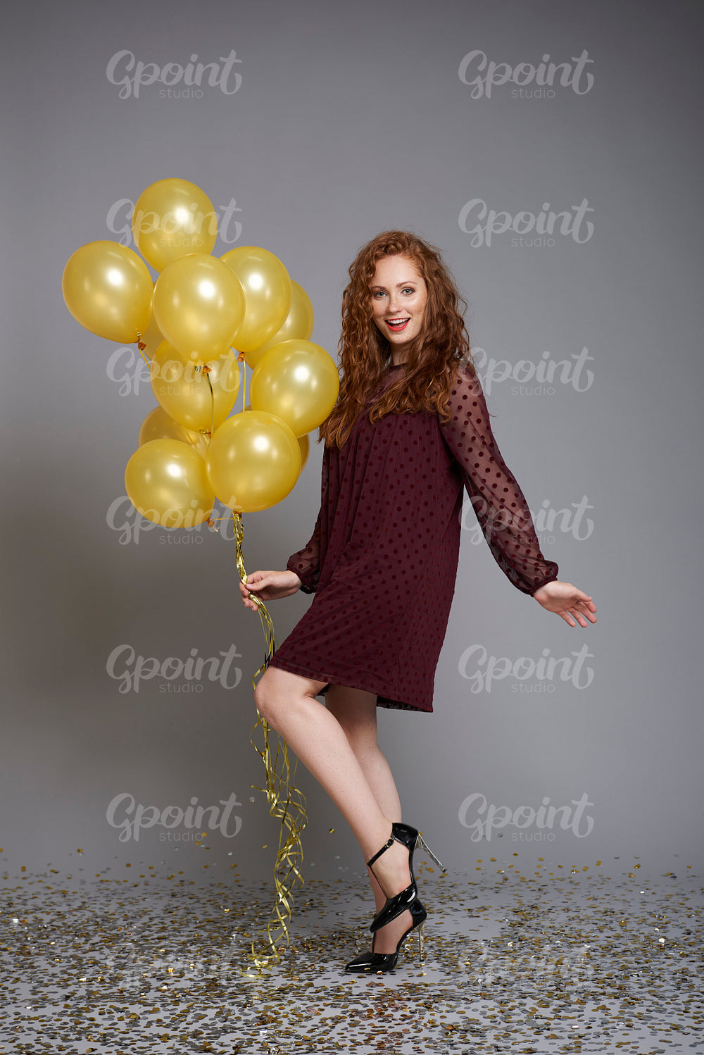 Portrait of smiling woman with bunch of balloons dancing