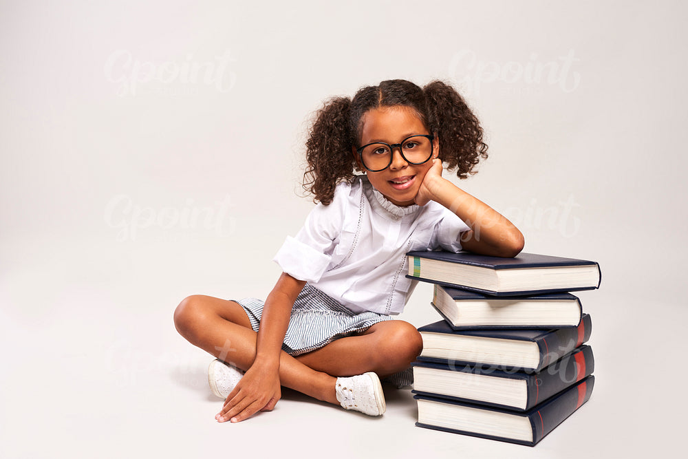 African girl sitting next to stack of books