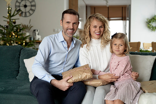 Portrait of caucasian family of parents and girl sitting and holding Christmas presents