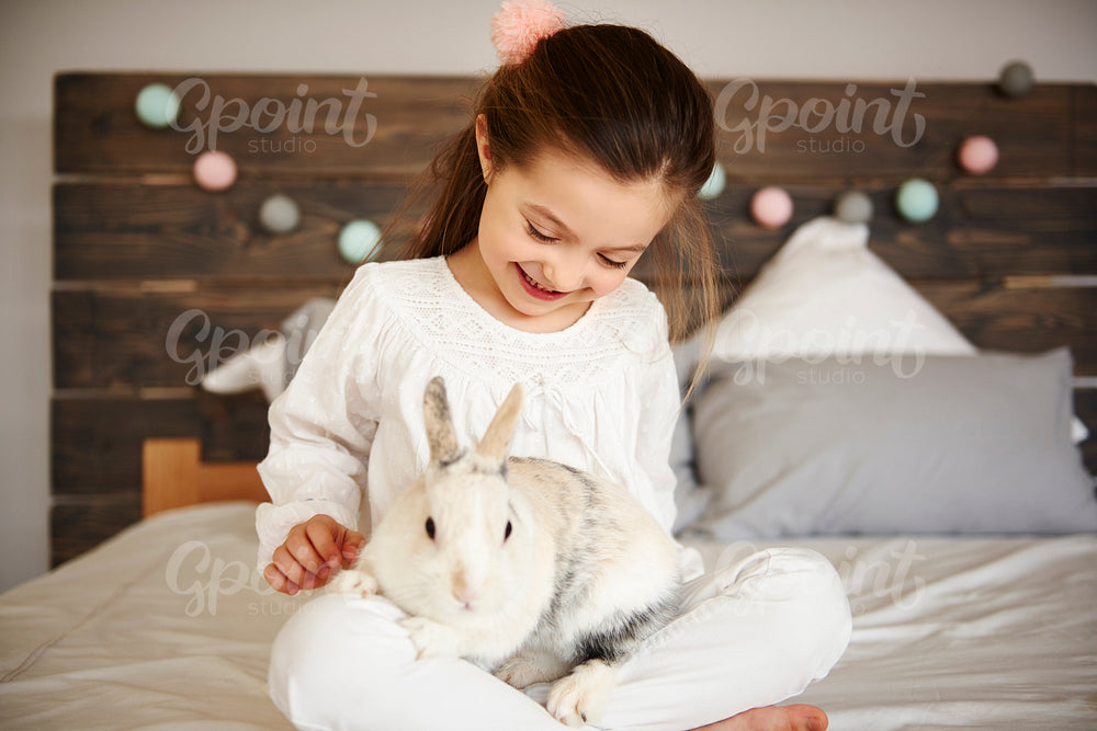 Happy girl and rabbit in bedroom