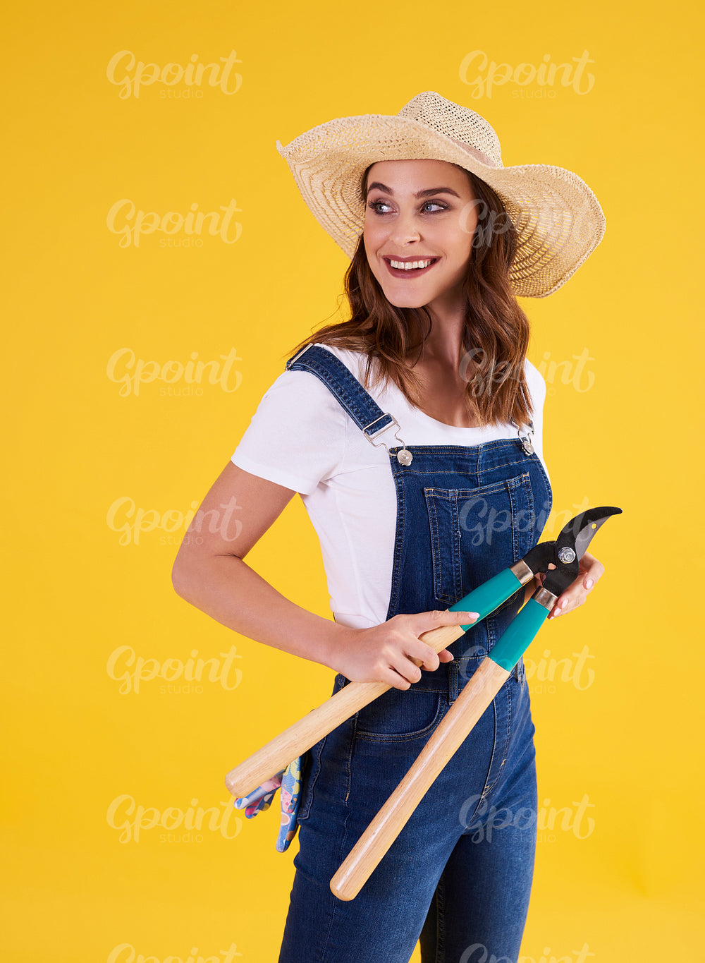 Smiling gardener holding hedge clippers in the studio shot