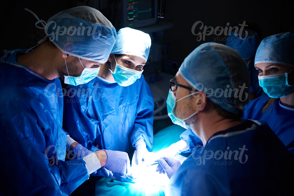 Team of surgeons in the dark operating room