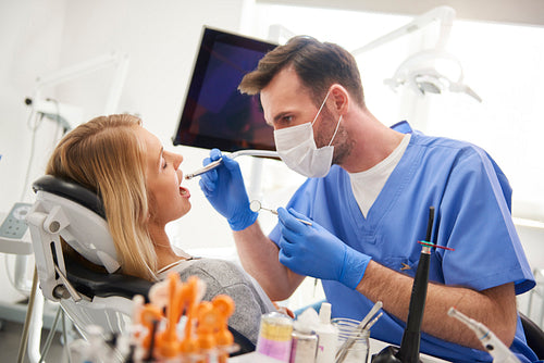 Focused dentist using dental drill and dental mirror