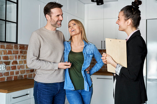 Happy couple talking to a real estate agent